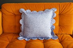 an orange couch with a blue and white pillow on it's backrest,