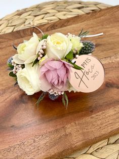 a bouquet of flowers sitting on top of a wooden table next to a name tag