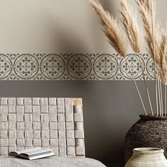 two vases with plants in them sitting next to a bed and wallpaper on the walls