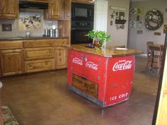 an old coca - cola cooler is in the middle of a kitchen with wooden cabinets