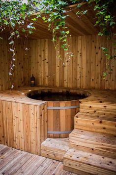 a wooden hot tub sitting on top of a wooden floor next to a green tree