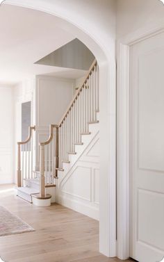 an archway leading to the second floor in a house with white walls and wood floors