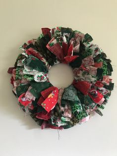 a christmas wreath made out of fabric on a white wall with red and green decorations