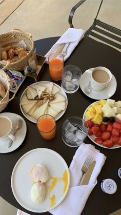 a table topped with plates of food next to cups of coffee and orange juices