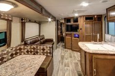 the interior of an rv with wood cabinets and marble counter tops, brown leather couches