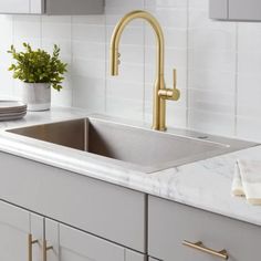 a kitchen sink with gold faucet and marble counter top