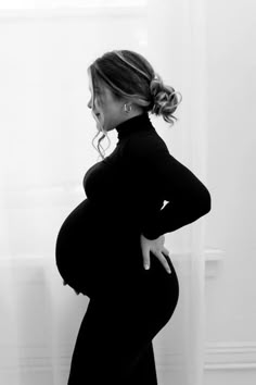 a pregnant woman standing in front of a window