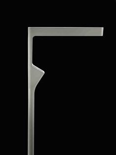 a black and white photo of a metal object on a black background with the letter t