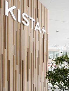 a large wooden wall with the words kista on it and a tree in front