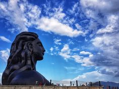 there is a large statue that looks like a head in the sky with clouds behind it