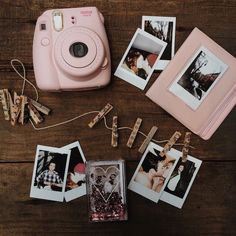 polaroid camera sitting on top of a wooden table next to photos and clothes pins