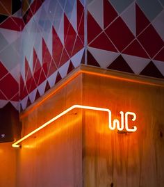 an illuminated sign on the side of a wooden building with red and white geometric wallpaper