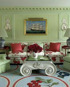 a living room filled with furniture and flowers on top of a table in front of a painting