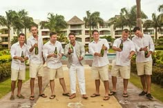 a group of men standing next to each other in front of a pool and palm trees