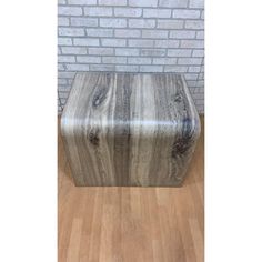 a wooden stool sitting on top of a hard wood floor next to a brick wall