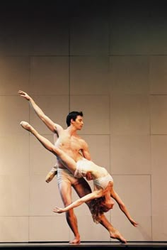 two dancers are performing in front of a wall