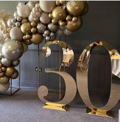 the number 50 is surrounded by balloons in gold, silver and white colors on display