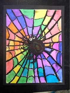 a stained glass window with a clock on it's face and spider web in the center