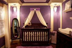 a baby crib in a room with purple walls and white drapes on the ceiling