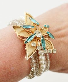 a close up of a person's arm wearing a bracelet with flowers and pearls