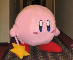 a large pink stuffed animal sitting on top of a floor next to a star shaped pillow