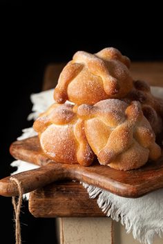 a pile of bread sitting on top of a wooden cutting board