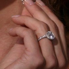 a close up of a person holding a ring and wearing it to her face with both hands