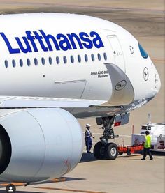 an lufthansa airplane is parked on the tarmac with workers around it