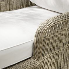 a wicker bed with white sheets and pillows on it's headrests