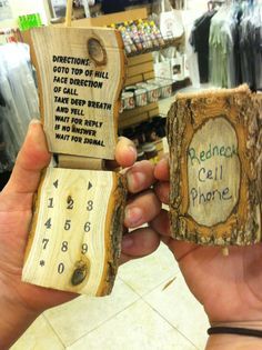 a person holding two pieces of wood with words on them in front of a store