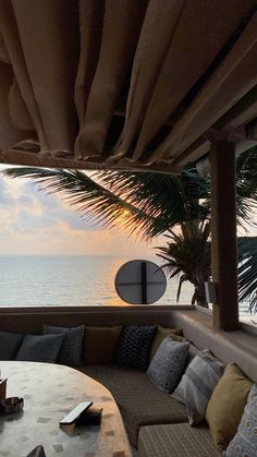 an outdoor seating area overlooks the ocean and beach at sunset, with a surfboard in the distance