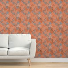 a white couch sitting in front of a wall with an orange and blue pattern on it