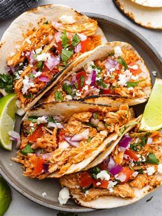 chicken tacos with cilantro, red onion and lime wedges on a plate