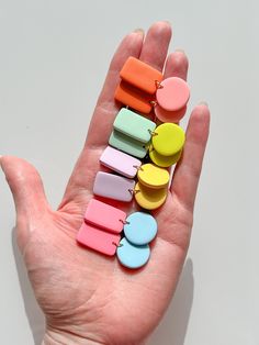 a person's hand holding several small pieces of colorful magnets on it,