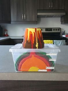 a cake in a plastic container sitting on top of a counter next to a stove