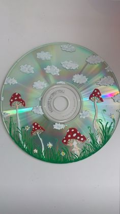 a cd that is sitting on top of a table with grass and mushrooms painted on it