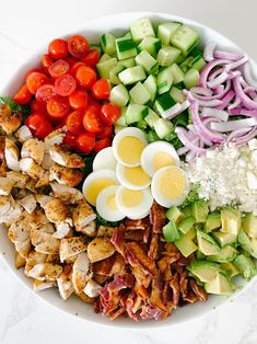 a salad with chicken, cucumbers, tomatoes, onions, and hard boiled eggs