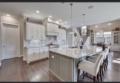 a large kitchen with white cabinets and marble counter tops