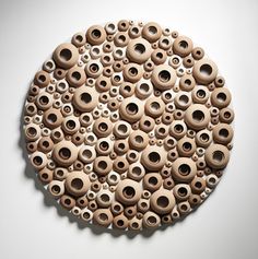 a circle made out of wooden beads on a white surface with one hole in the middle