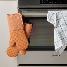 two oven mitts are hanging on an oven door