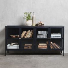 a black cabinet with books and vases on top