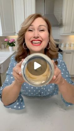 a woman is holding up a bowl in the middle of her hands and smiling at the camera