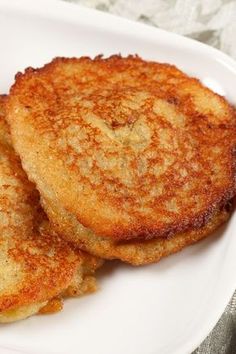 two pancakes on a white plate sitting on a table