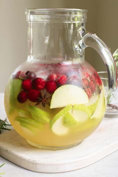 a pitcher filled with fruit and berries on top of a counter