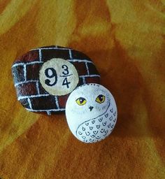 two painted rocks sitting on top of a yellow and brown blanket next to each other