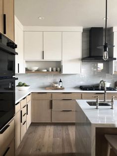 a kitchen with wooden floors and white cabinets, black appliances and an island in the middle