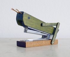 a green stapler sitting on top of a wooden block