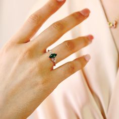 a woman's hand with a ring on it and a green stone in the middle