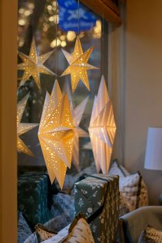 three paper stars hanging from the ceiling in front of a window with pillows on it