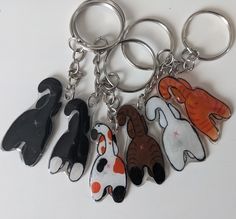 four keychains with different designs on them sitting next to each other in the shape of dogs